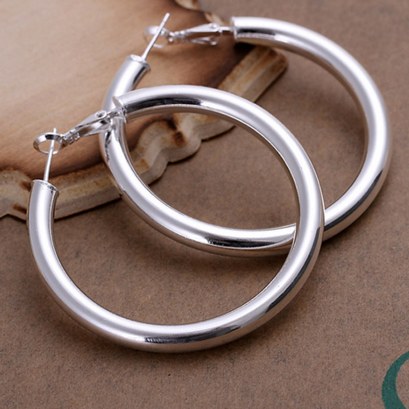 Silver-tone hollow hoop earrings with wide round hoops and visible hinge clasp