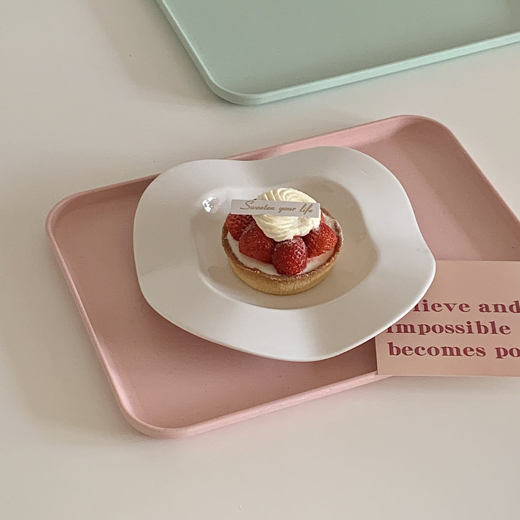 Single white wave-shaped ceramic plate with an oval center well holding dessert