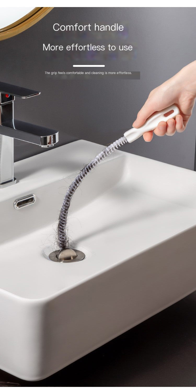 Hair-cleaner brush held toward sink drain, long coiled bristles for clearing buildup
