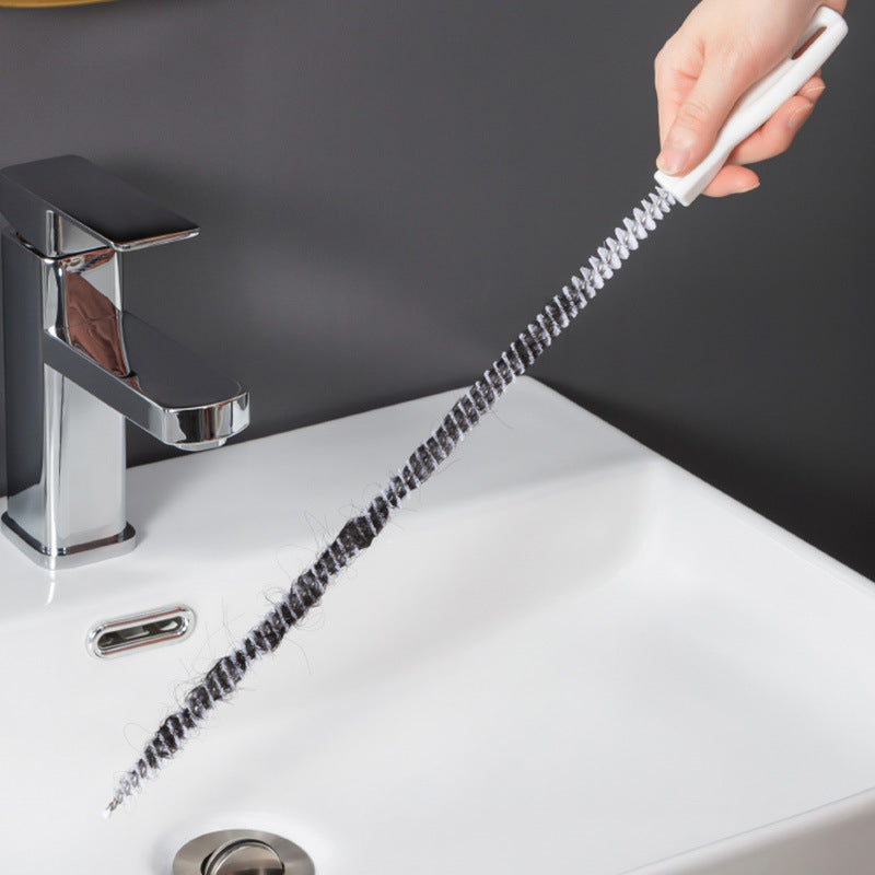 White brush with long coiled bristles for clearing hair from a bathroom sink drain