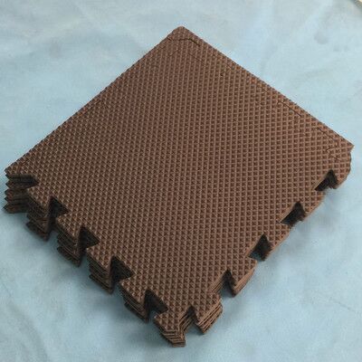 Brown foam puzzle floor mat with interlocking edges, square tiles stacked