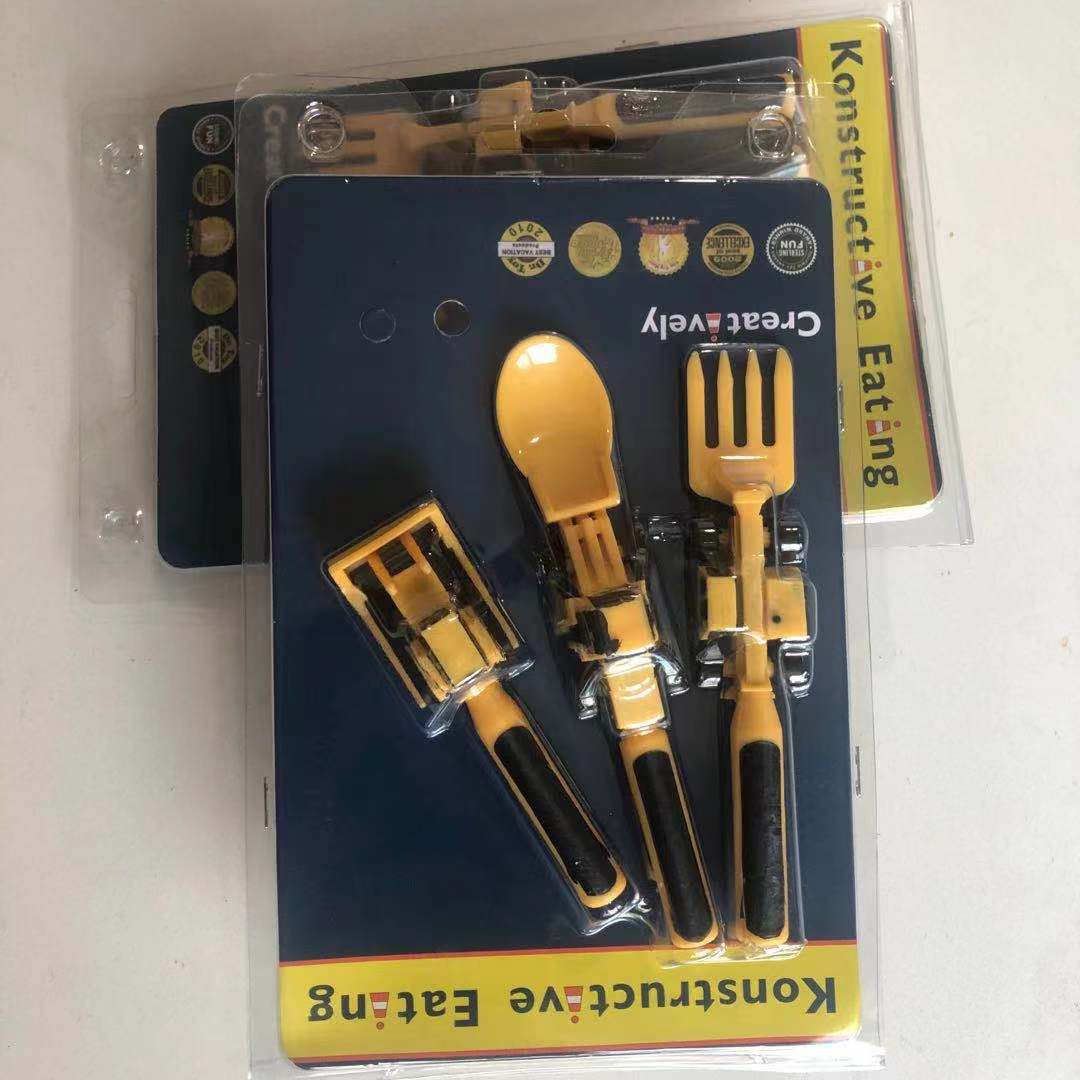 Juego de cubiertos amarillos infantiles en blister: cuchara y tenedor con insertos negros.