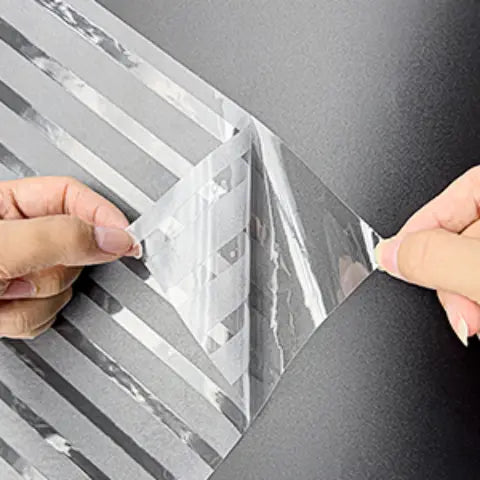 Frosted-Stripe-Fensterfolie, Hände richten und glätten die Folie auf dem Glas