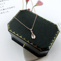 Rose-gold chain necklace with pink teardrop quartz charm on dark jewelry box