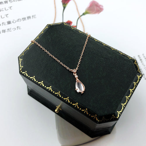 Rose-gold chain necklace with pink teardrop quartz charm on dark jewelry box