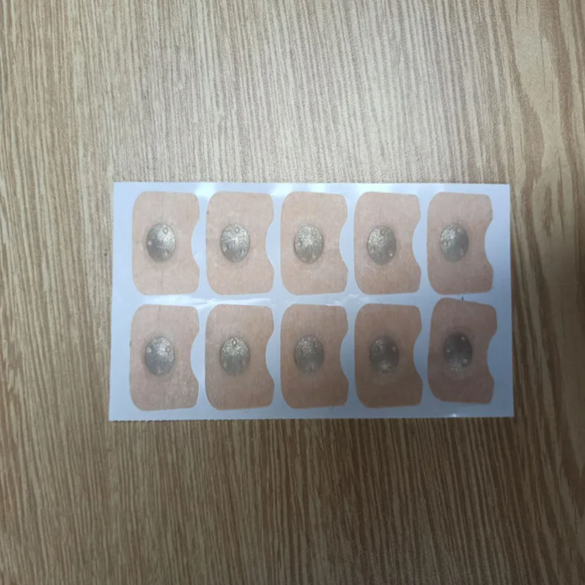 Square nose patches on backing sheet, light beige with dark gray centers