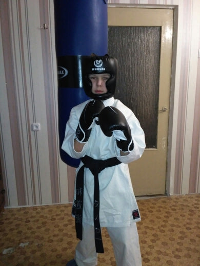 Black headgear worn with white martial arts gloves; face opening and chin guard