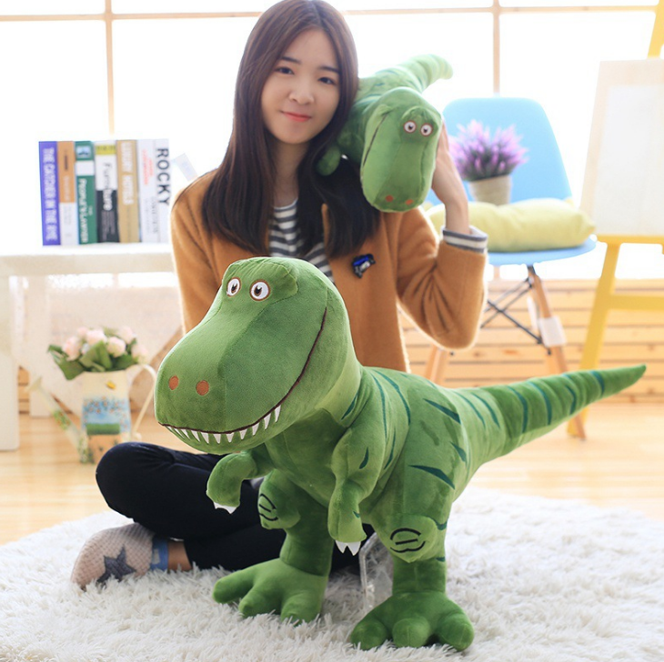 Green plush T-Rex dinosaur toy posed with long tail, embroidered face and orange eye accents