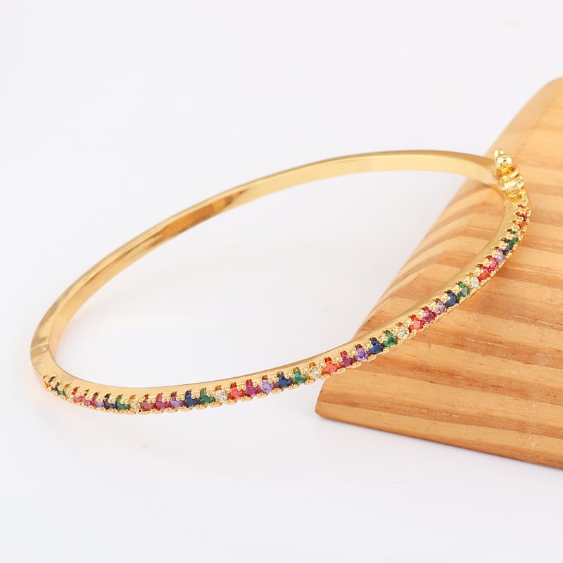 Gold bracelet with rainbow multicolor stones along the band, curved view