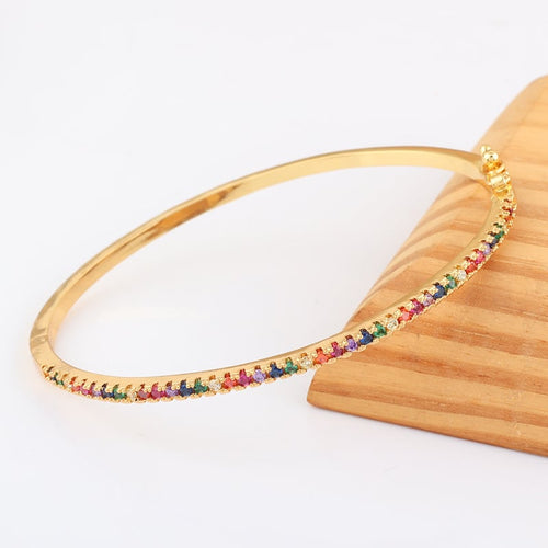 Gold bracelet with rainbow multicolor stones along the band, curved view