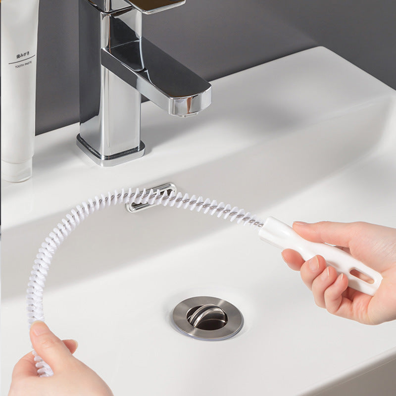 Coiled bristle hair-cleaner brush being pulled through a round sink drain opening