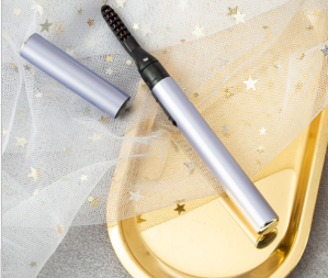 Silver electric eyelash curler with black heated comb tip and gold base