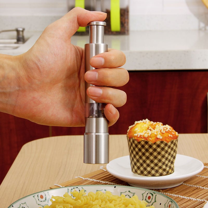 SmartGrip pepper grinder held in hand, brushed silver body and clear top section