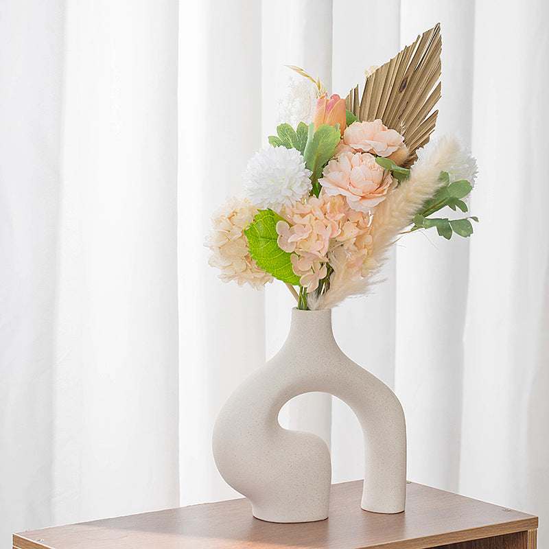 Tall beige ceramic vase with side cut-out, styled with mixed flowers on tabletop