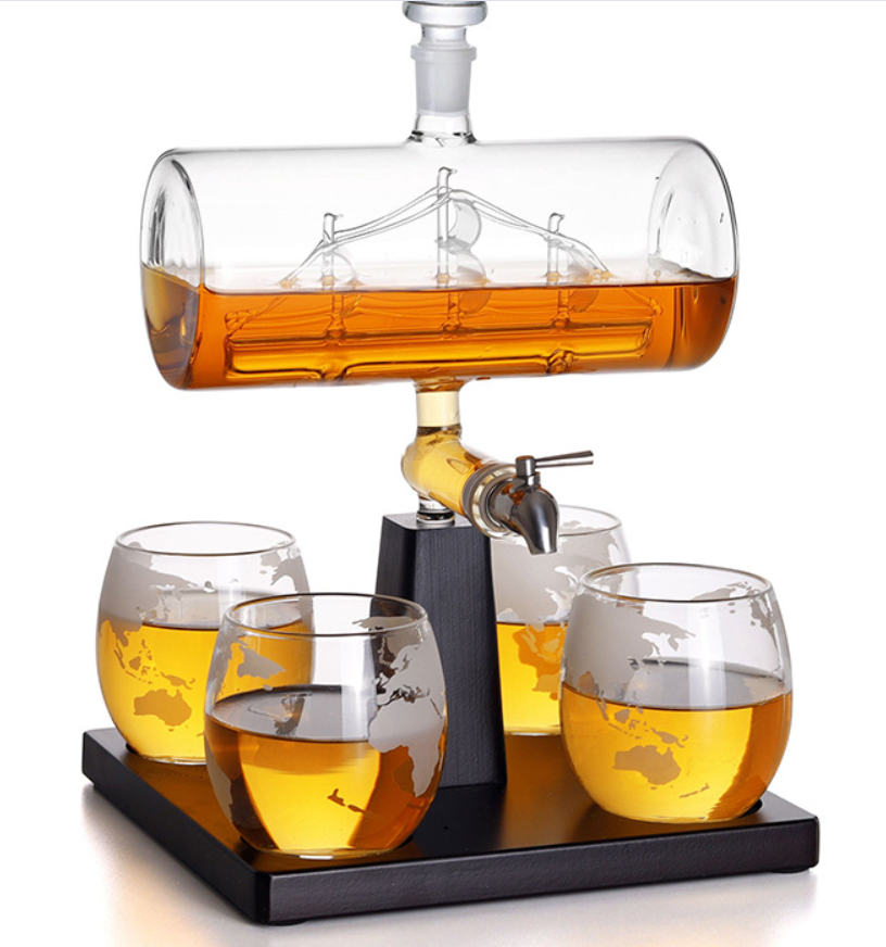 Amber-filled glass wine bottle container with tap, globe tumblers on black base