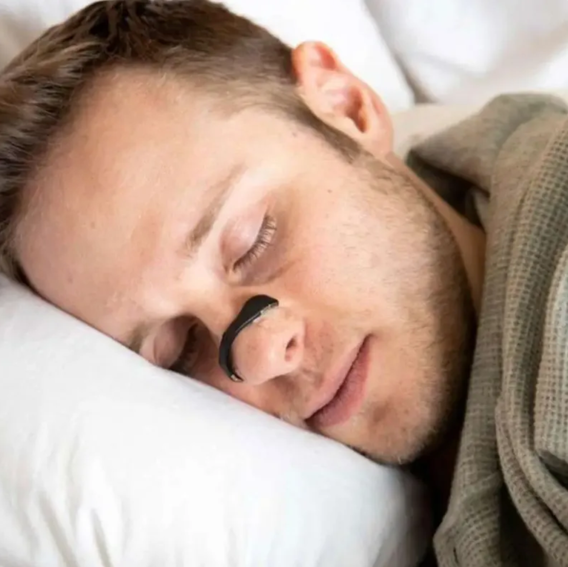 Black nasal dilator worn on nose while sleeping, nose strip visible