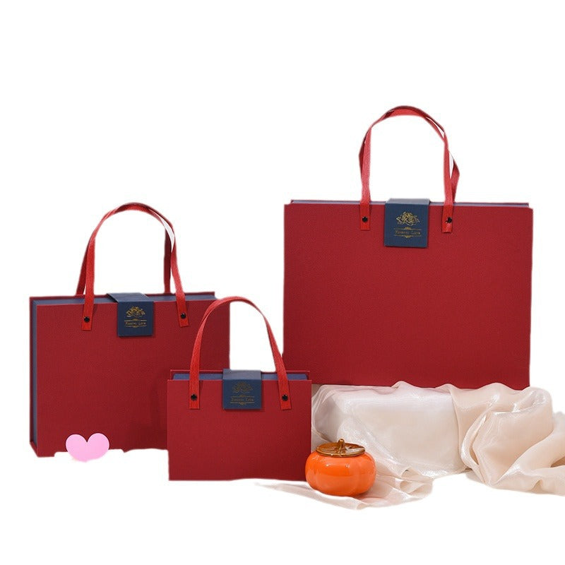 Chinese red gift box set with red handle straps and logo badge, three nested sizes