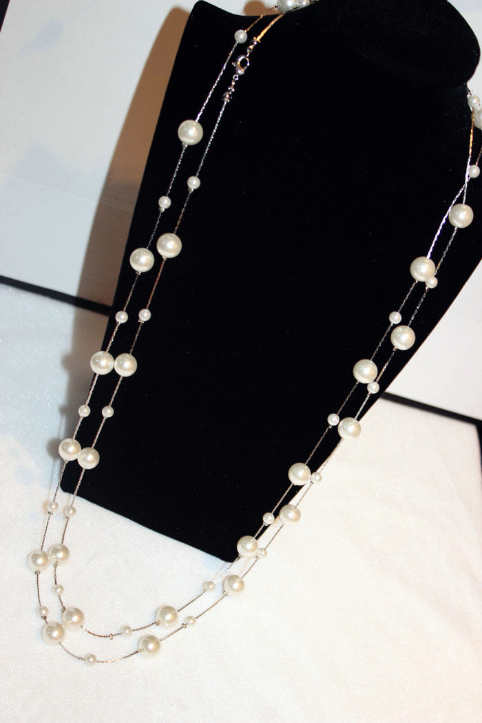 Silver-tone pearl-like bead chain necklace on black display, layered long strands