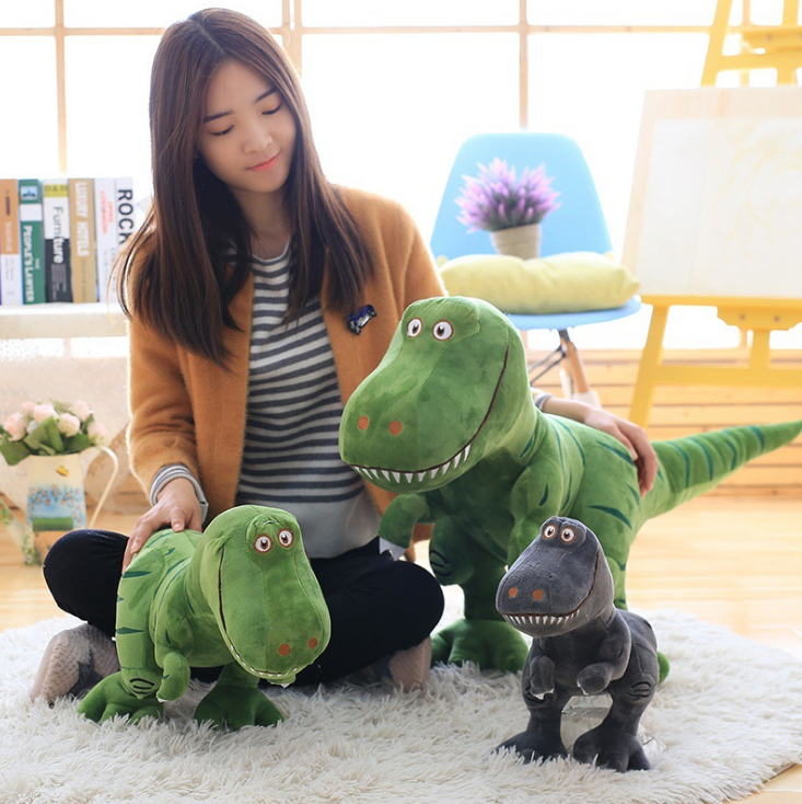 Green plush T-Rex held by child, with stitched grin and long tail in foreground