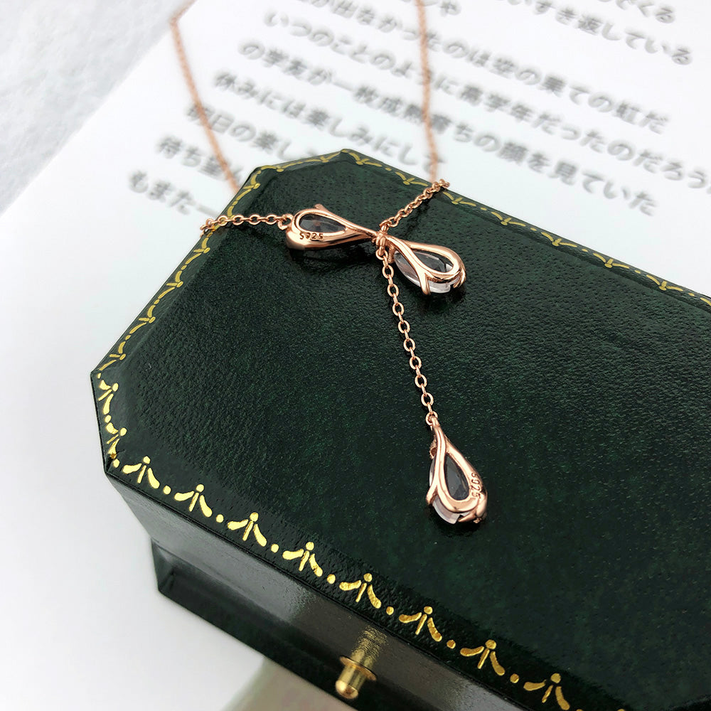 Rose-gold necklace clasp with pink teardrop quartz drops on dark jewelry box