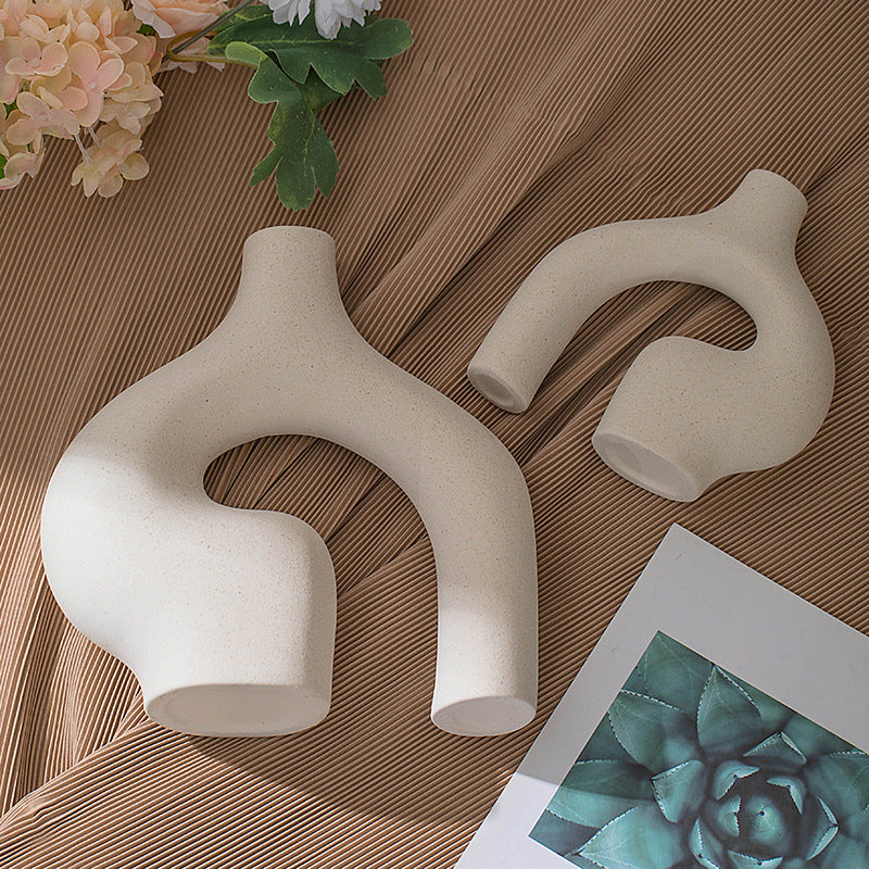 Beige ceramic vase with arched side cut-out and small opening, styled with flowers