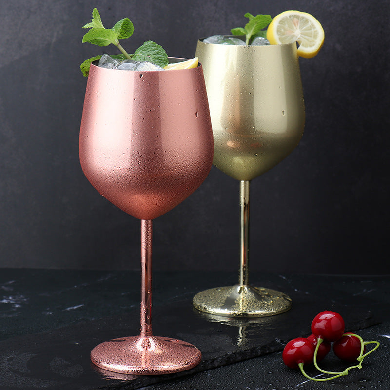 Copper and bronze-plated wine goblets with ice cubes, rounded bowls and tall stems