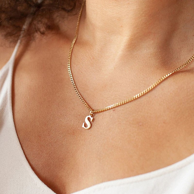 Gold letter S pendant necklace on a person’s neckline