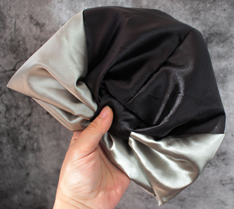 Doppellagige Satin-Schlafhaube in Schwarz mit silbergrauen Seiten, gefaltet