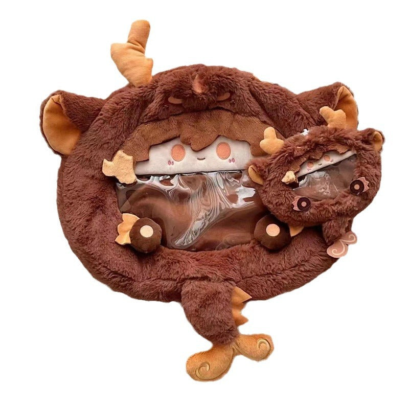 Brown plush dragon backpack with sleepy face and antler horns, open inner pouch
